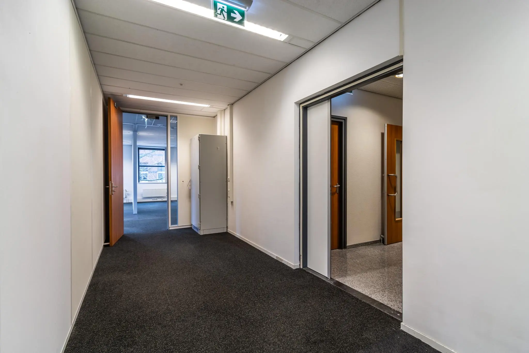 Hal met deuren naar kantoorkamers in een bedrijfsgebouw aan de Lange Dreef.